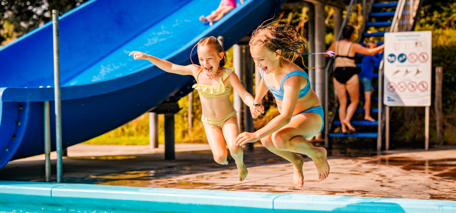 Twee meiden die een sprong maken in het zwembad