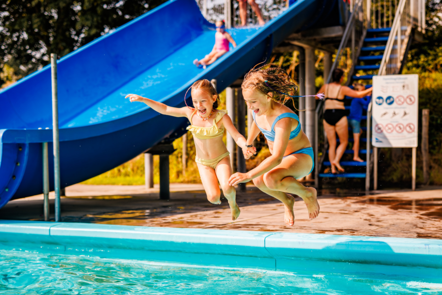 Twee meiden die een sprong maken in het zwembad