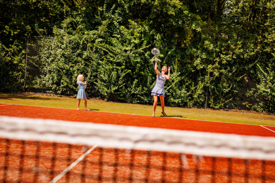 Gezin dat gratis gebruikt maakt van de tennisbaan op het vakantiepark