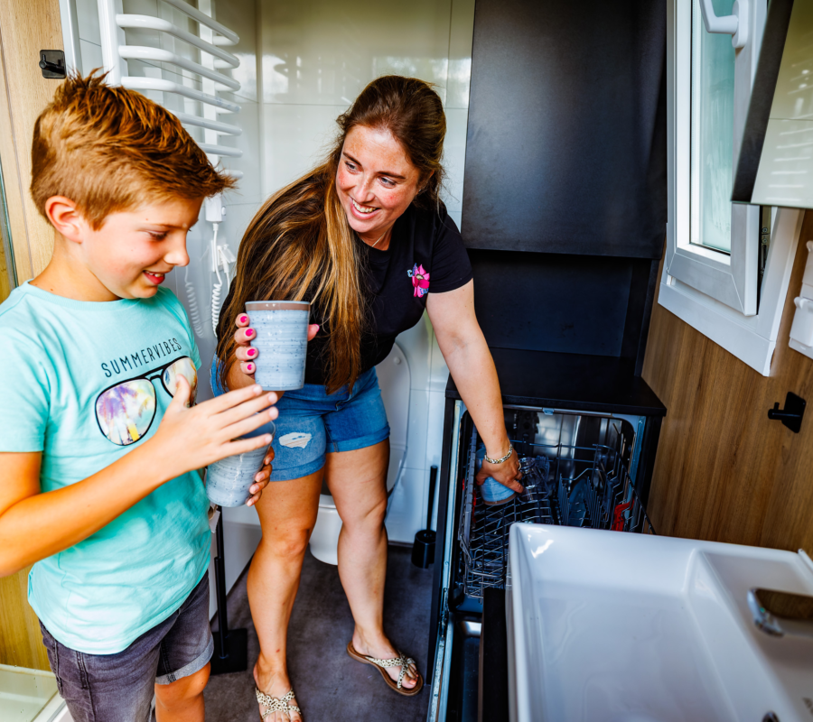Gezin gebruikt de vaatwasser binnen het privé sanitair op camping almelo